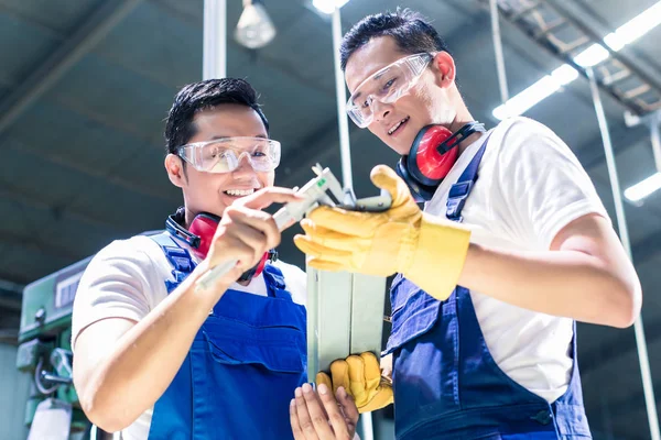 Dos trabajadores industriales inspeccionando la pieza de trabajo — Foto de Stock
