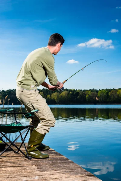 Pesca del pescatore al lago in piedi sul molo — Foto Stock