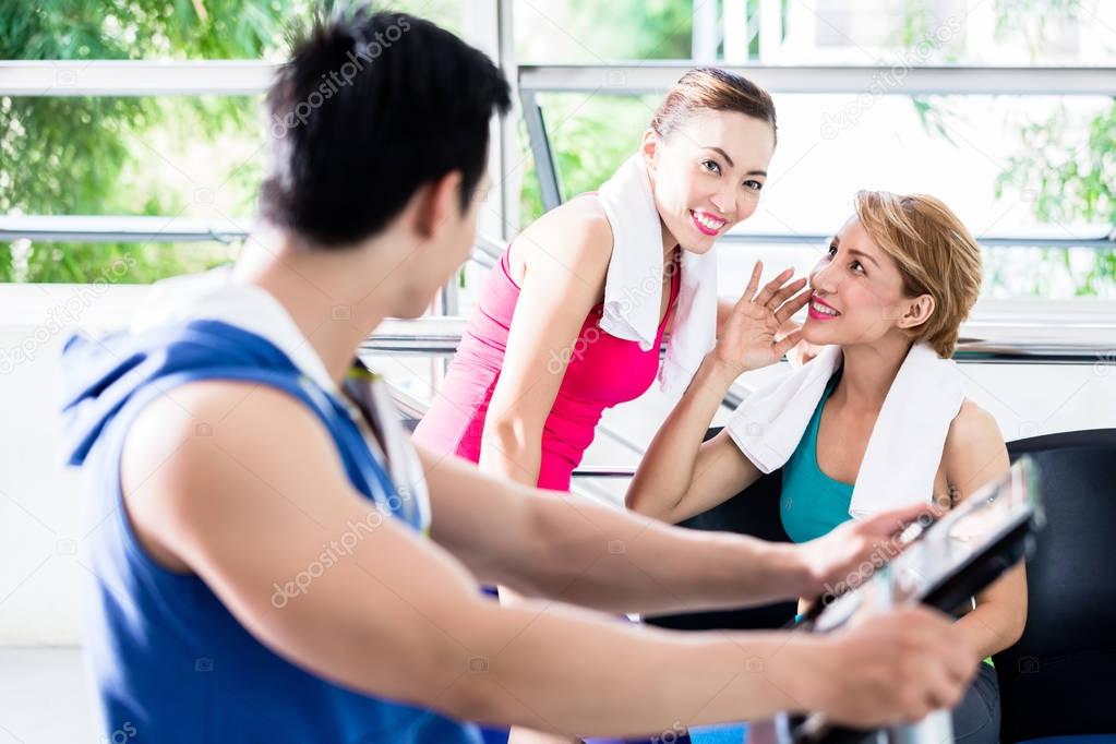 sportive man on treadmill flirting with smiling girls