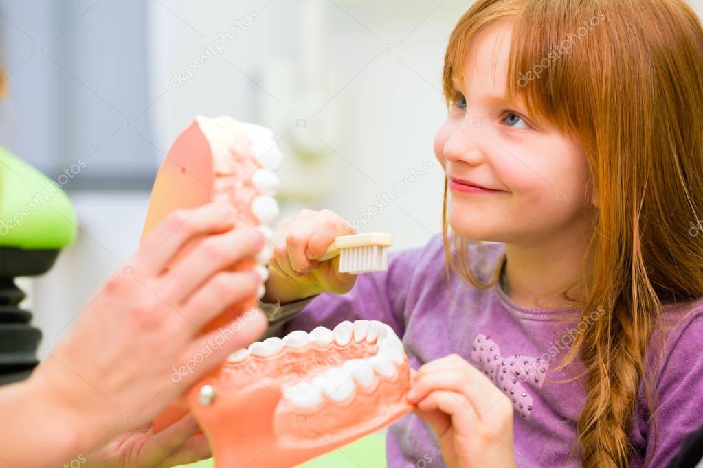 Dentist explaining girl cleaning tooth 