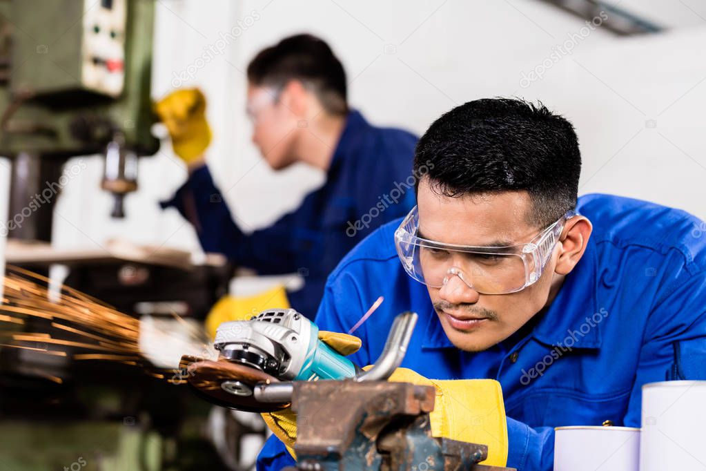 Metal workers in industrial workshop grinding