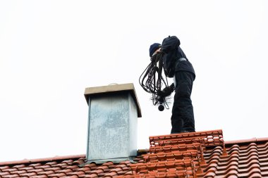 Chimney sweep on roof of home working