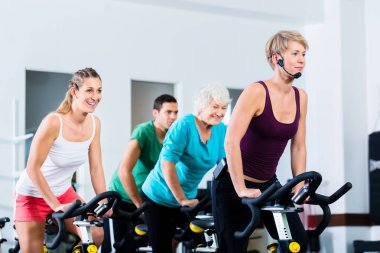 Spor salonunda fitness bisiklet üzerinde iplik üst düzey insanlar
