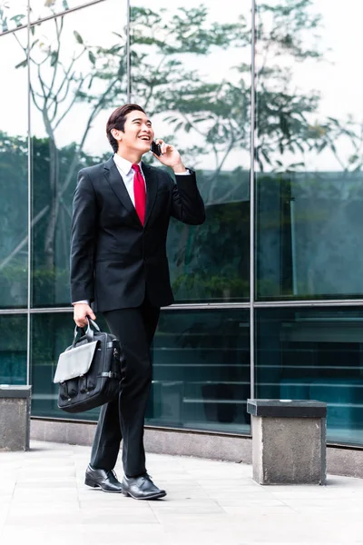 Aziatische zakenman praten met mobiele telefoon buiten — Stockfoto