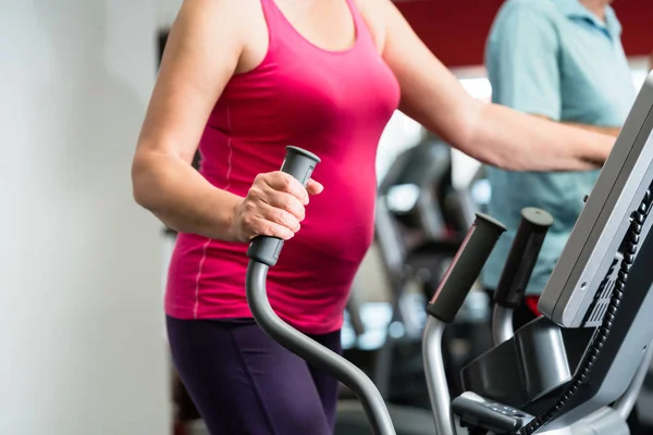 Elderly woman training on cross trainer