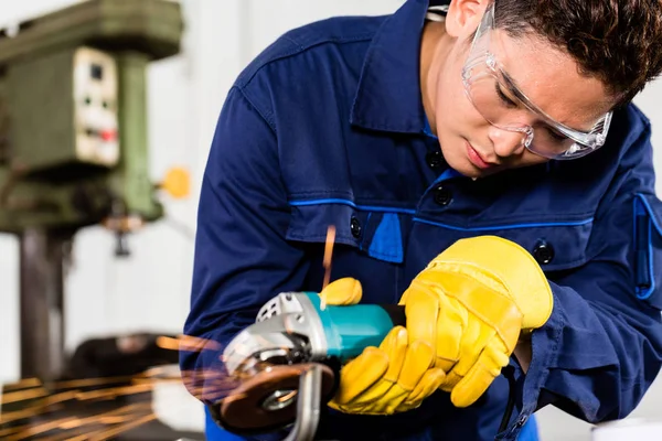 Trabajador asiático moliendo metal en planta de fabricación — Foto de Stock