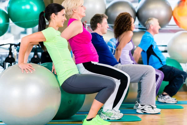 Grupo de jóvenes y personas mayores que hacen ejercicio en el gimnasio — Foto de Stock