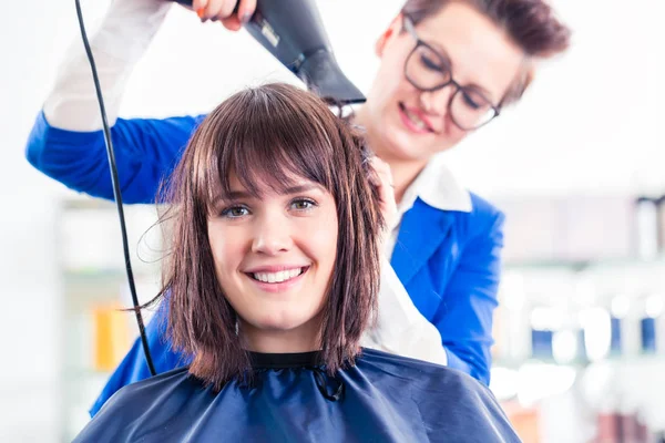 Coiffeur souffler cheveux femme sèche dans le magasin — Photo