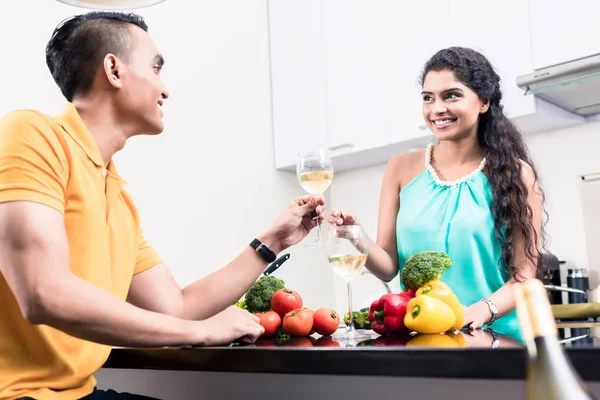 Indiase vrouw en man in de keuken met rode wijn — Stockfoto