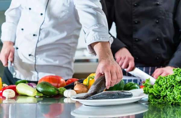 Chef-koks bereiden van voedsel in teamwork bij restaurant keuken — Stockfoto