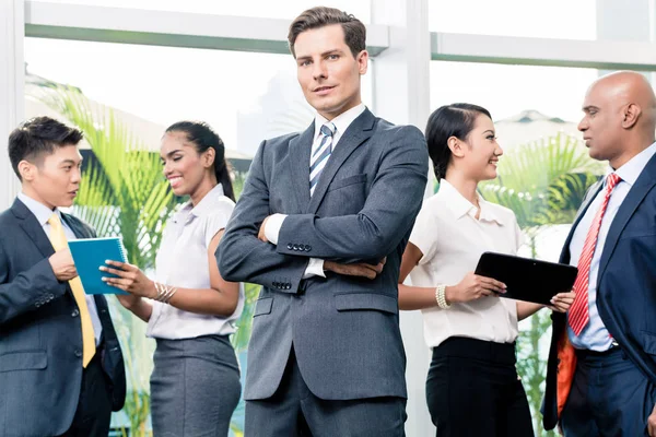 Business team meeting with man in front looking at camera — Stock Photo, Image