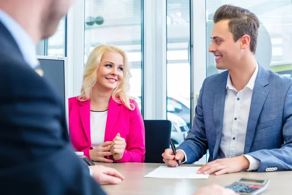 Man signing sales contract for auto at car dealership — Stock Photo, Image