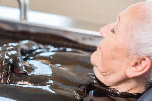 Senior woman enjoying mud bath — Stock Photo, Image