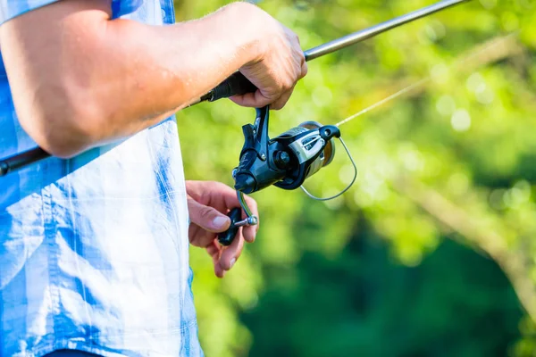 Cerrar tiro de pescador deportivo tambaleándose en línea en la caña de pescar —  Fotos de Stock