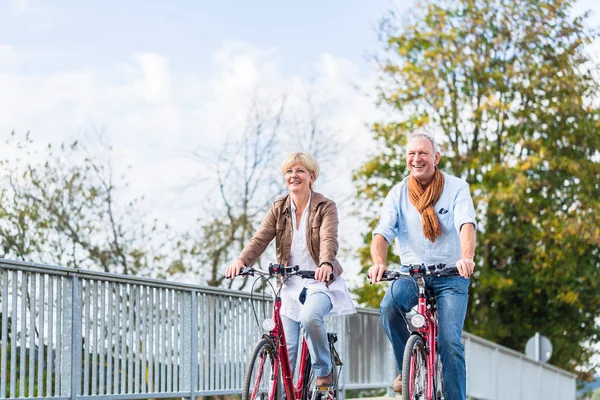 Seniorenpaar mit Fahrrädern auf Brücke — Stockfoto