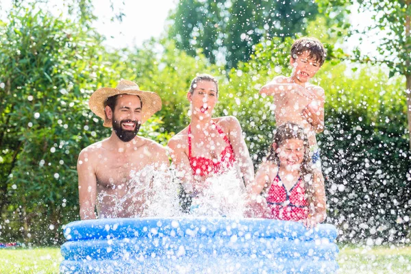 Familie kühlt Spritzwasser im Gartenpool ab — Stockfoto