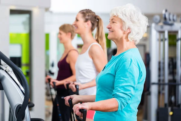 Vecchi e giovani su piastre vibranti in palestra — Foto Stock