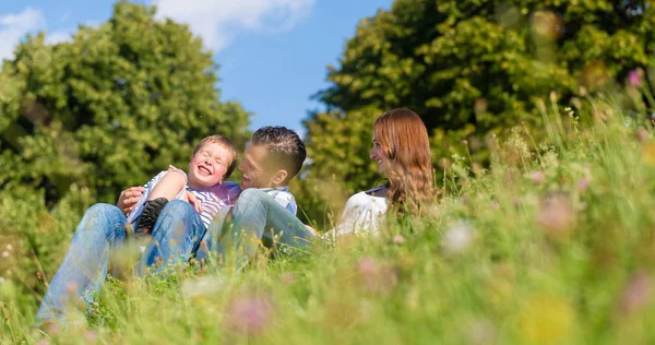 Familia abrazos sentado en el prado — Foto de Stock