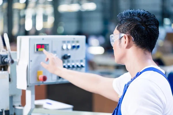 Worker pressing buttons on CNC machine in factory — Stock Photo, Image