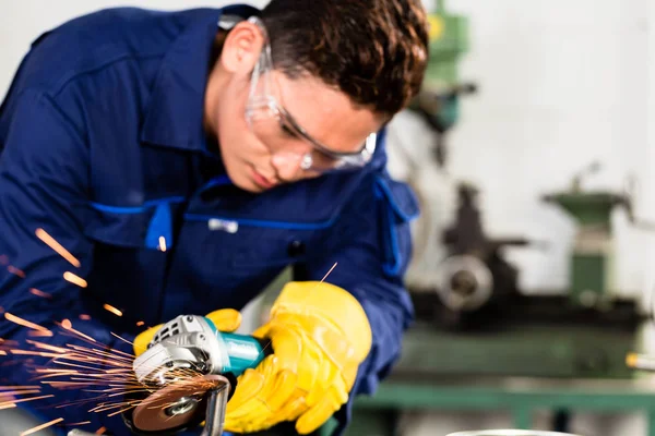 Trabajador asiático moliendo metal en planta de fabricación — Foto de Stock