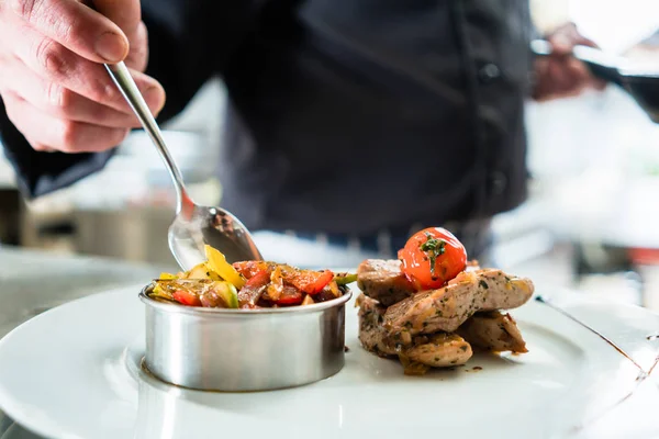 Chef-kok afwerking van voedsel op de plaat in restaurant keuken — Stockfoto