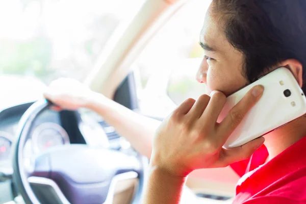 アジア人の男性が車を運転している間電話をかける — ストック写真