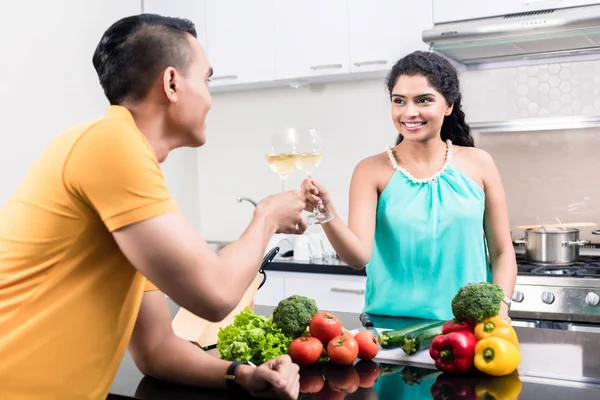 Hintli kadın ve erkek kırmızı şarap ile mutfakta — Stok fotoğraf