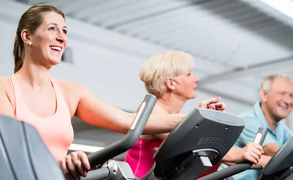 Jeune femme et couple de personnes âgées filant à la salle de gym — Photo