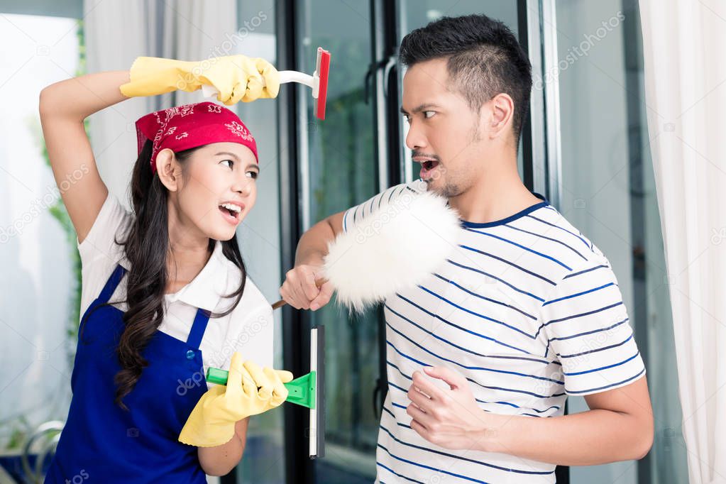Asian woman and man having fun cleaning home