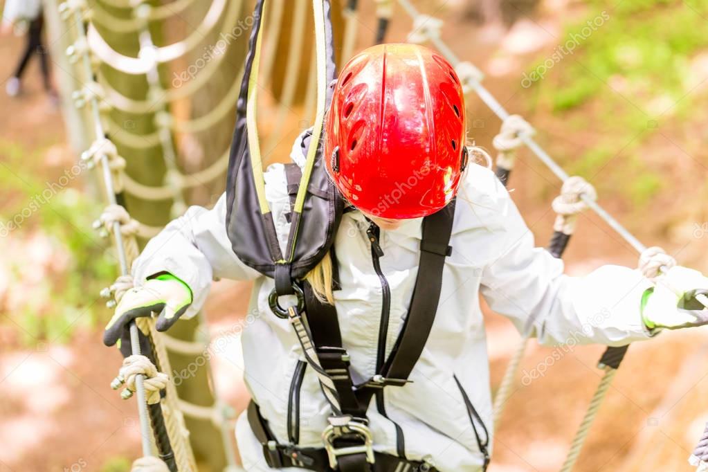 Girl seen from above climbing in high rope course