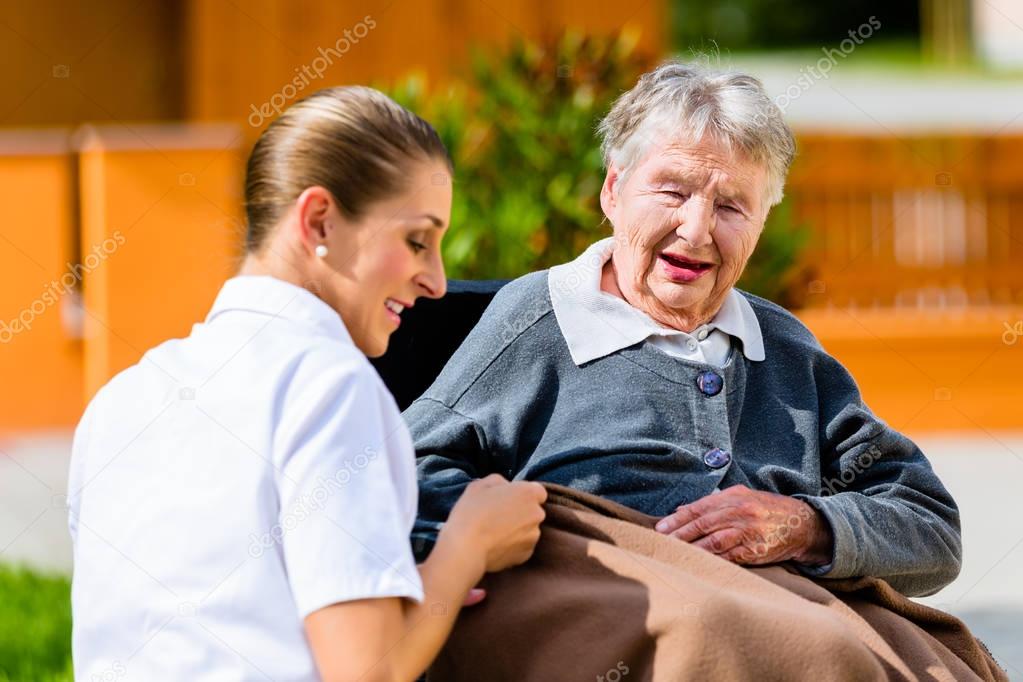 Nurse holding hands with senior woman in wheelchair