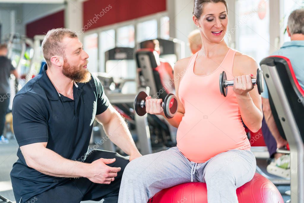 Pregnant woman working out with personal trainer 