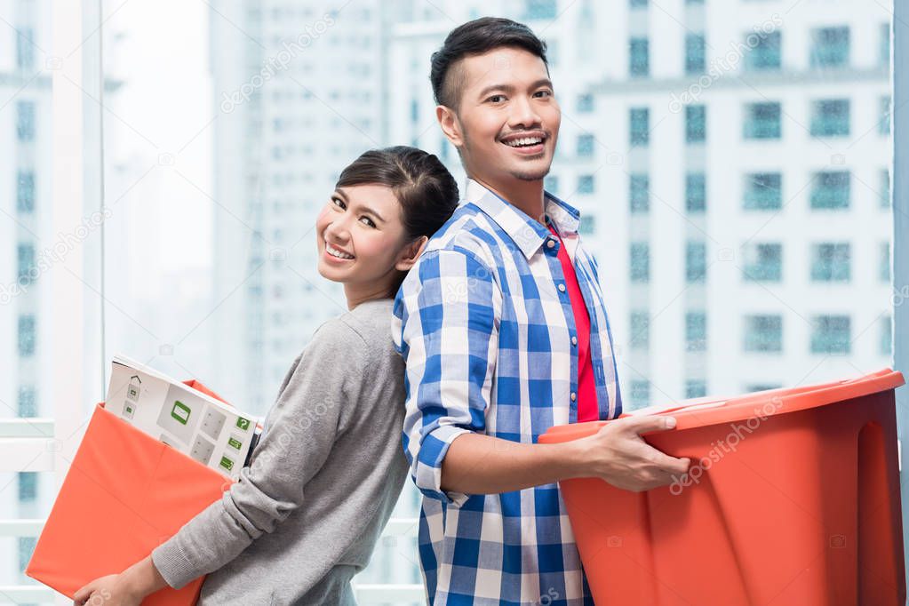Young indonesian couple carrying moving boxes 