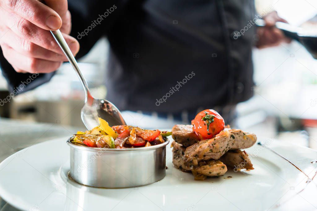 Chef finishing food on plate in restaurant kitchen