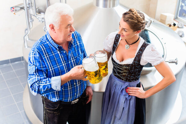 Brewer and woman toasting beer 