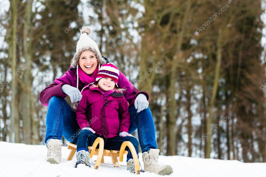 Woman and daughter on sled in winter