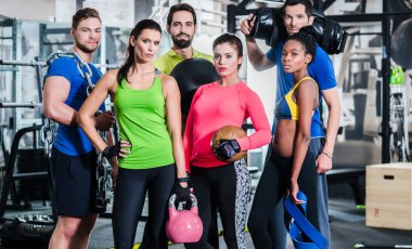 Group of women and men in gym posing at fitness training clipart