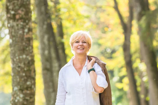 Mujer mayor caminando en el bosque de otoño — Foto de Stock