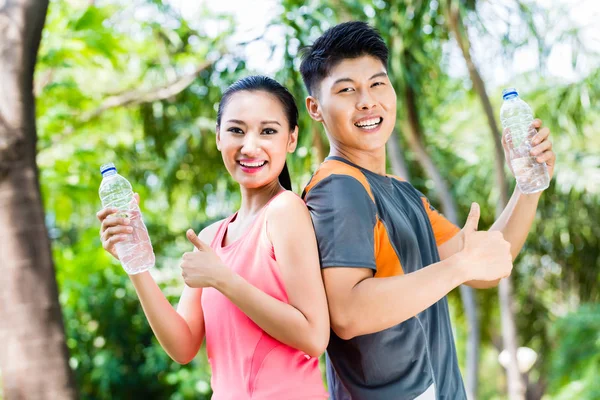 Asiatisches Paar trinkt Wasser nach Sport im Park — Stockfoto