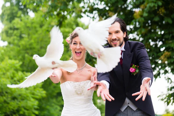 Brautpaar mit fliegenden weißen Tauben — Stockfoto