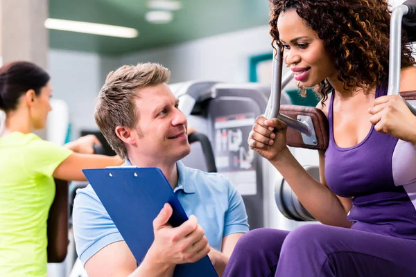 Fitnesstraining im Fitnessstudio - schwarze Frau und Personal Trainer — Stockfoto