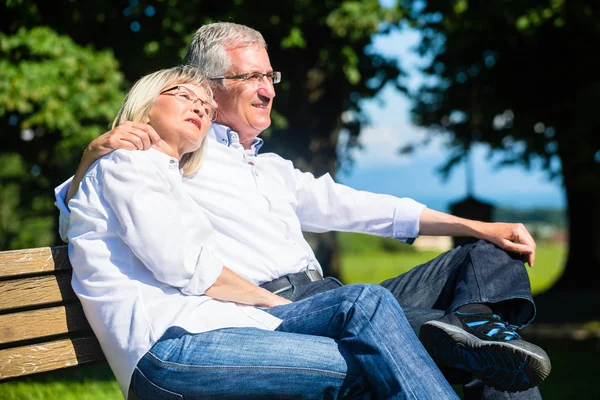 Senior woman and man resting on bench embracing — Stock Photo, Image