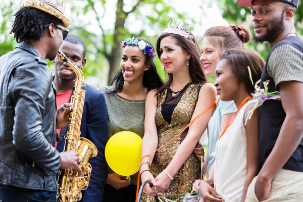 Straßenkünstler spielt Saxofon für multi-ethnische Gruppe — Stockfoto