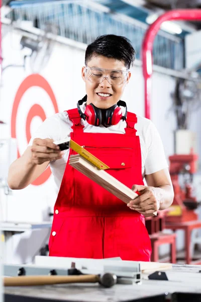 Asiatischer Tischler misst Stück Holz — Stockfoto