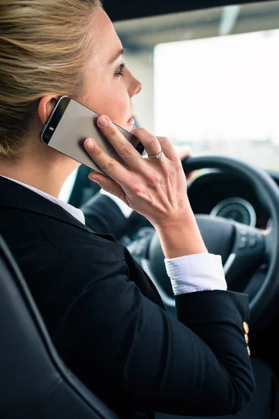 Frau benutzt ihr Handy während der Autofahrt — Stockfoto