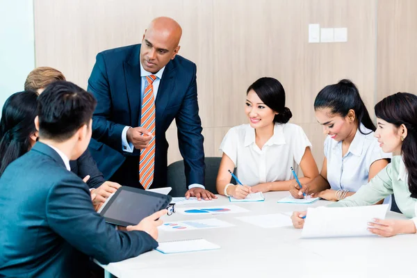 Diversity team in business development meeting with charts — Stock Photo, Image