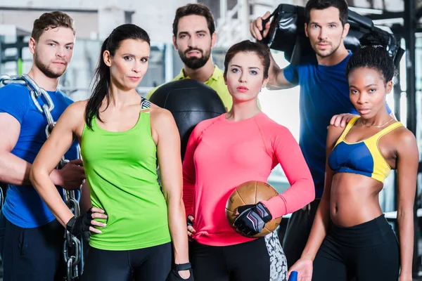 Grupo de mujeres y hombres en el gimnasio posando en el entrenamiento de fitness —  Fotos de Stock