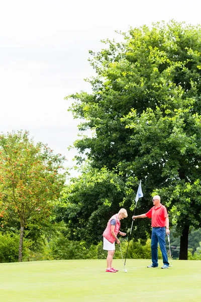 Äldre kvinna och man spelar golf — Stockfoto