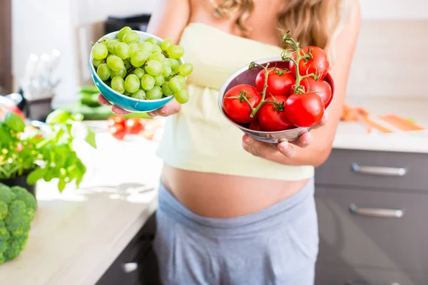 Zwangere vrouw tonen van groenten en fruit — Stockfoto