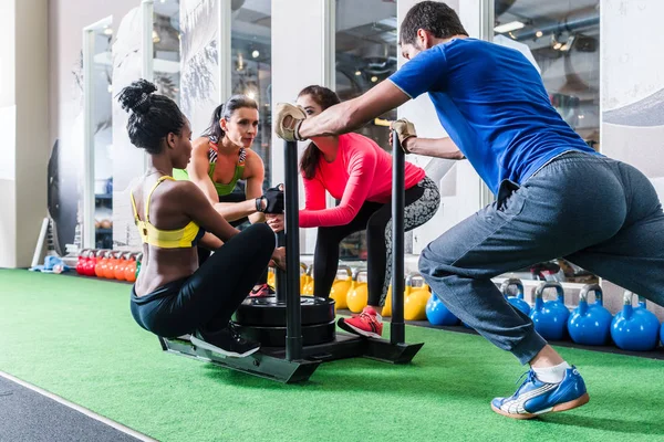 Homem empurrando as mulheres no carrinho como exercício de fitness — Fotografia de Stock